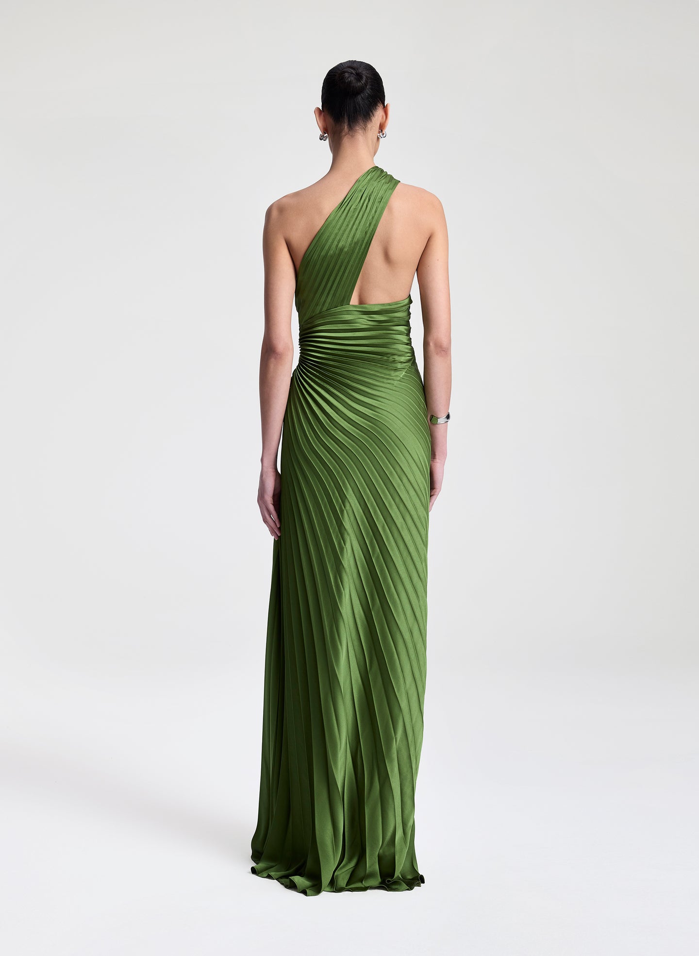 Woman wearing a green one-shoulder pleated dress on a white background