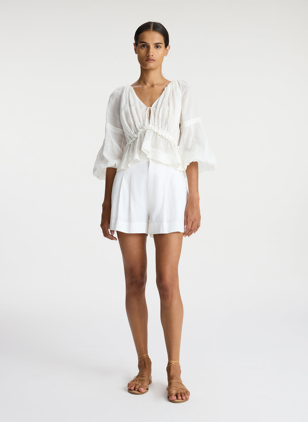 front view of woman wearing white blouse and white shorts