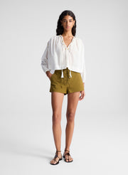 woman wearing white blouse and green lace up detail shorts