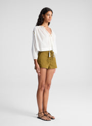 woman wearing white blouse and green lace up detail shorts