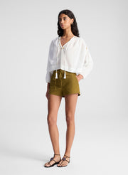 woman wearing white blouse and green lace up detail shorts