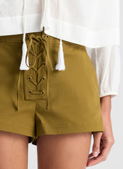 woman wearing white blouse and green lace up detail shorts