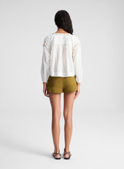 woman wearing white blouse and green lace up detail shorts