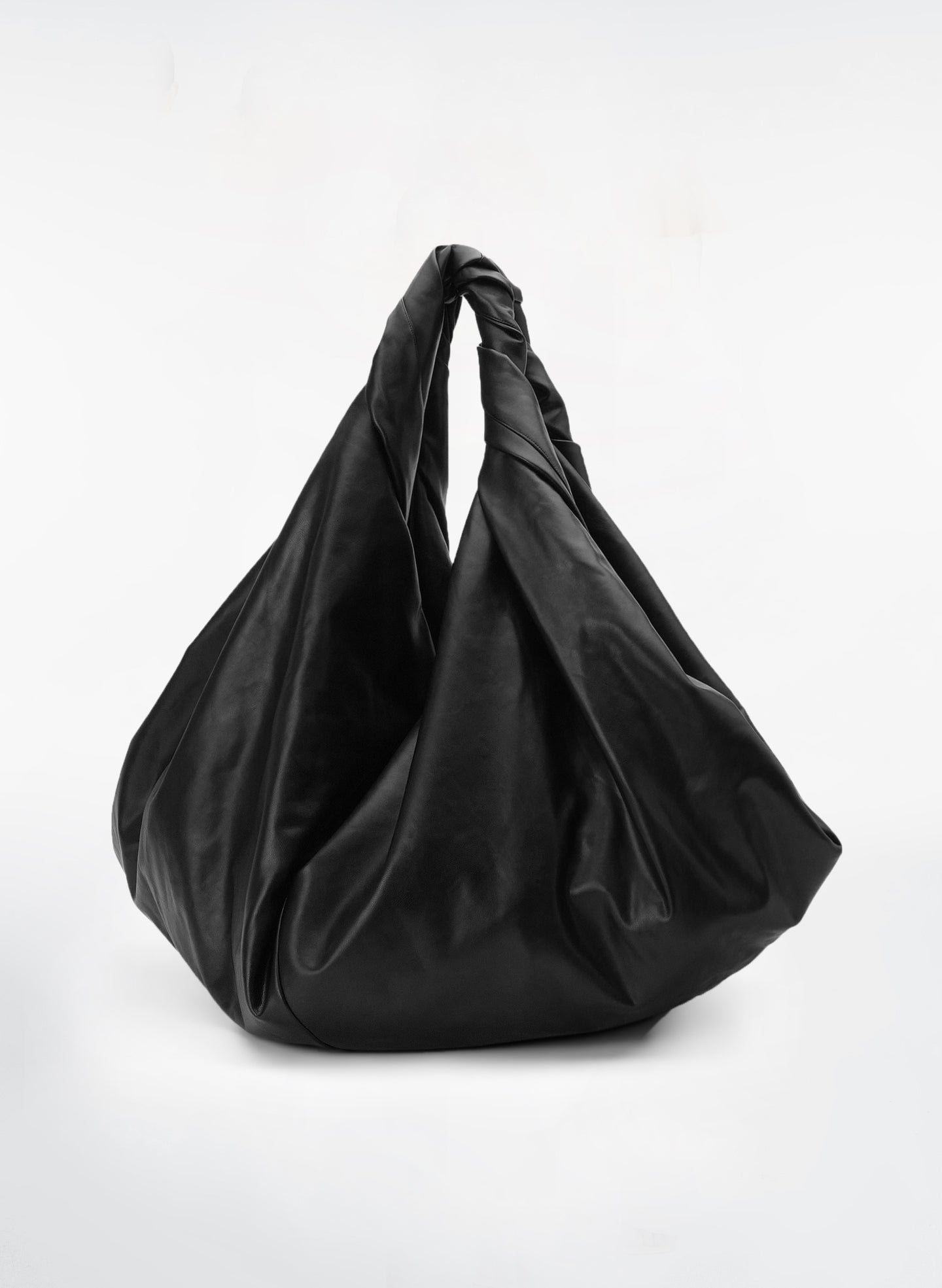 flat lay view of black vegan leather medium length top handle bag with medium sized rectangular base