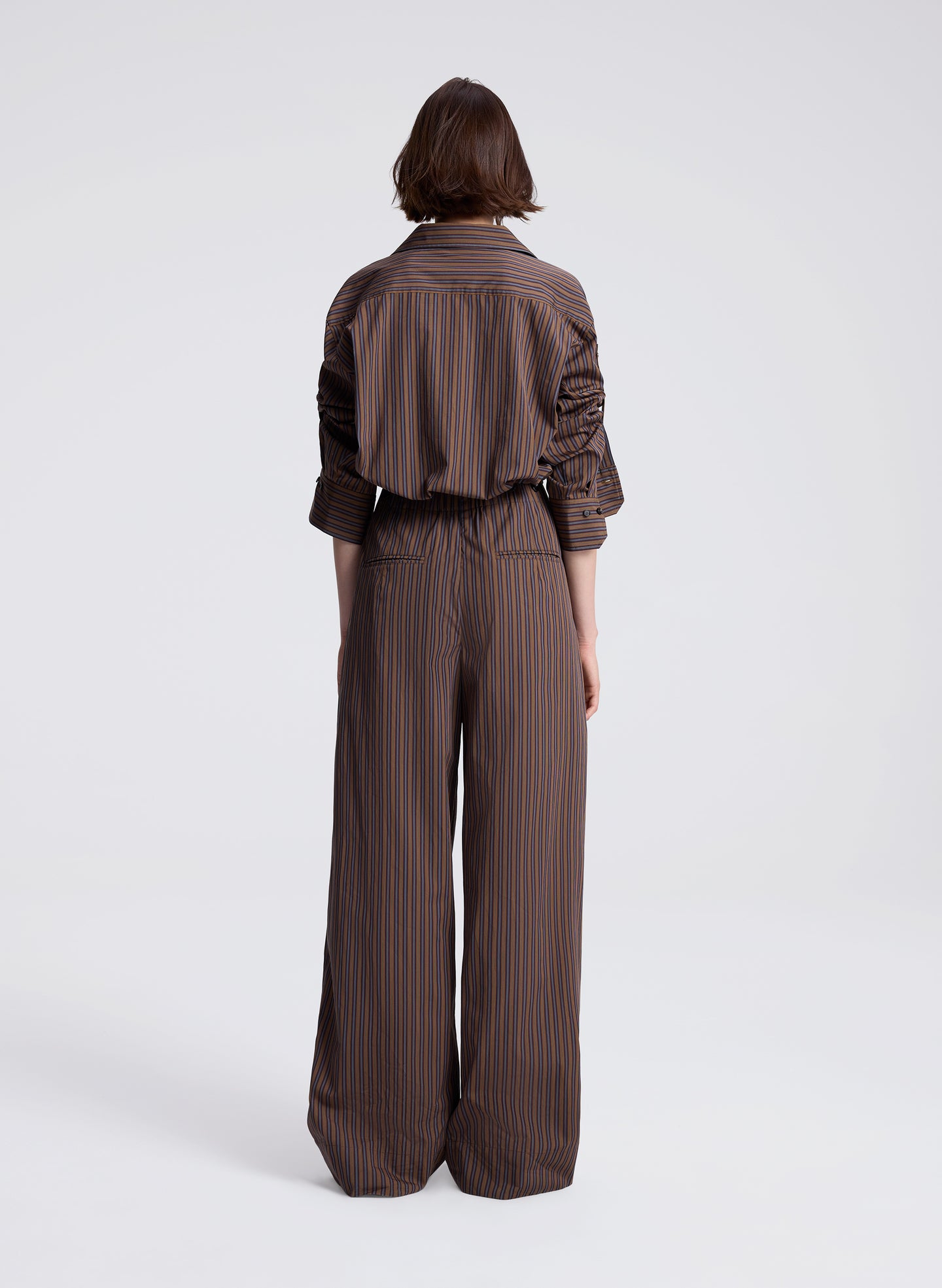 woman wearing brown button down shirt and matching set brown striped pants