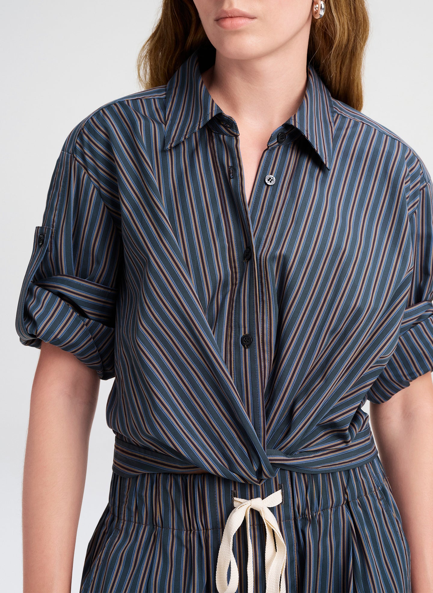 Woman wearing a blue and brown striped shirt with a white background