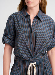 Woman wearing a blue and brown striped shirt with a white background