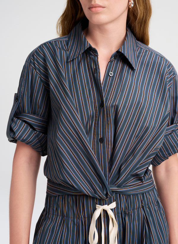 Woman wearing a blue and brown striped shirt with a white background