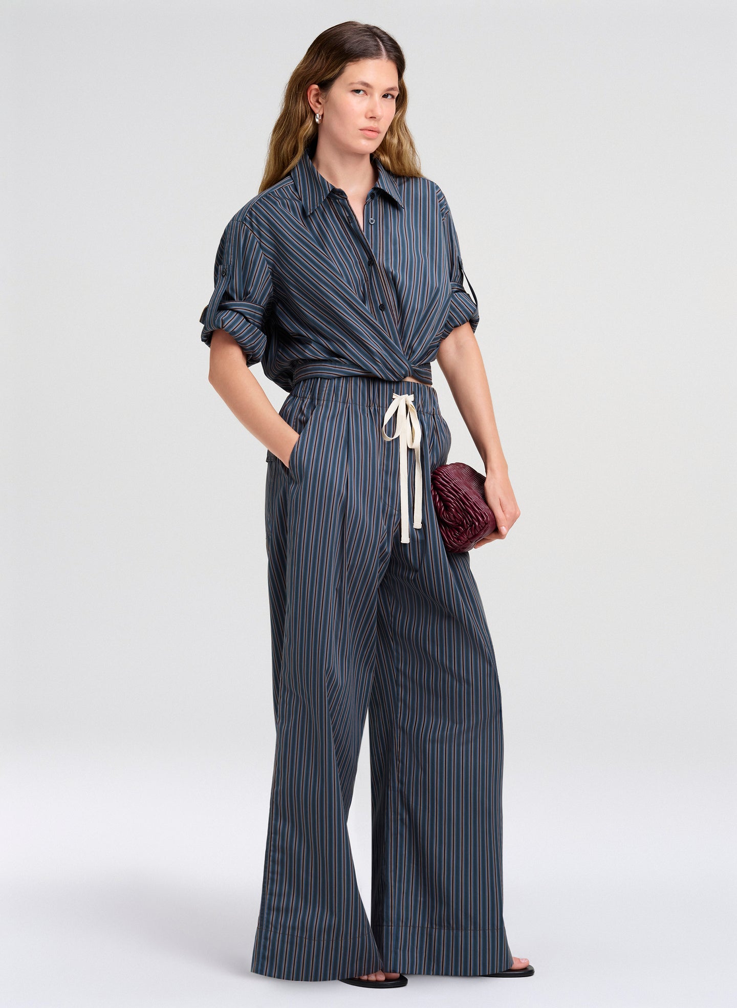 Woman wearing a blue striped top and pants on a white background