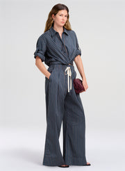 Woman wearing a blue striped top and pants on a white background