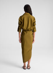 woman wearing olive green shirt and matching draped olive green midi skirt