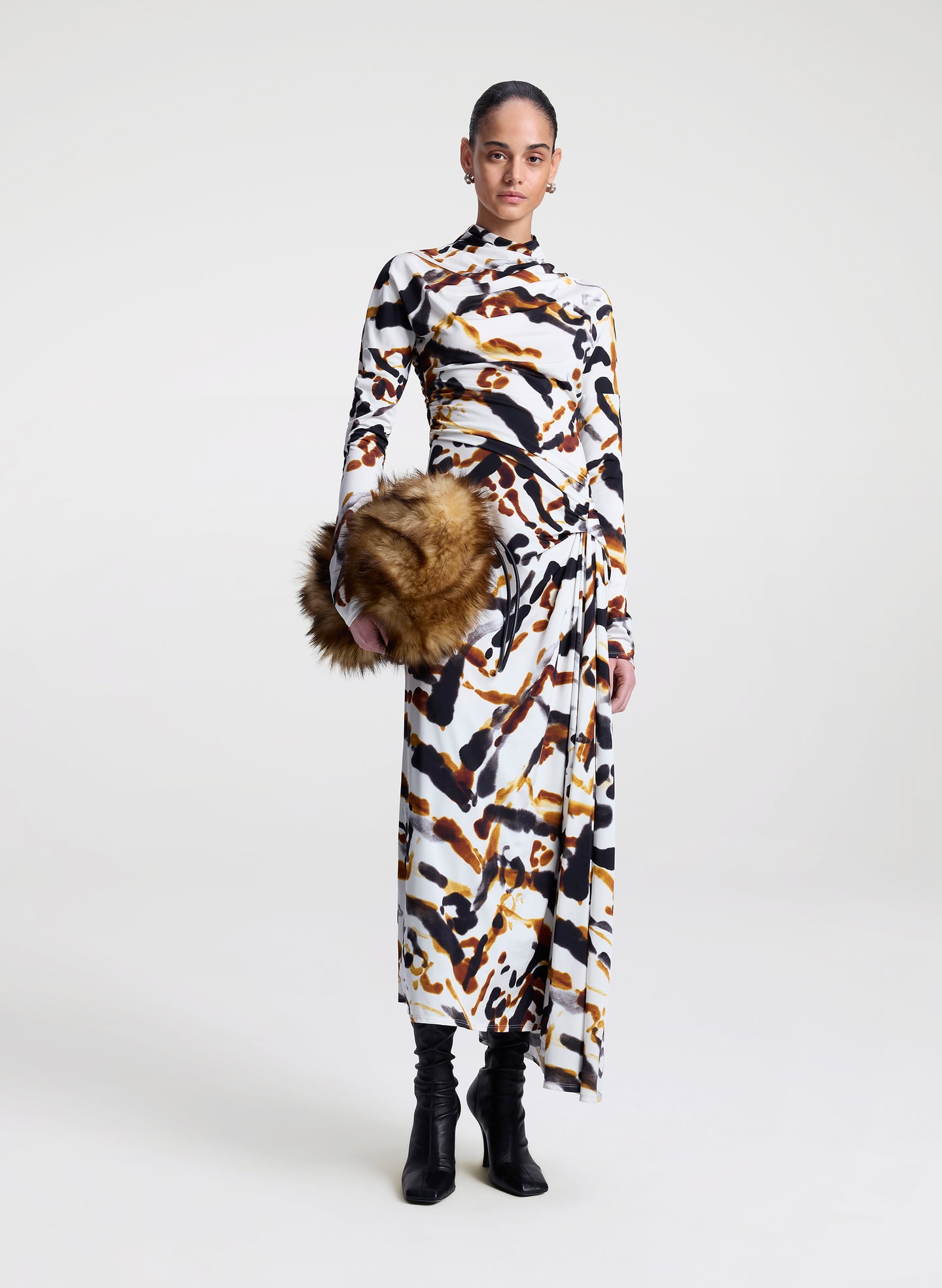 Model wearing a patterned dress with a faux fur bag on a white background