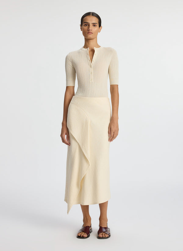 front view of woman wearing beige short sleeve shirt and cream midi skirt