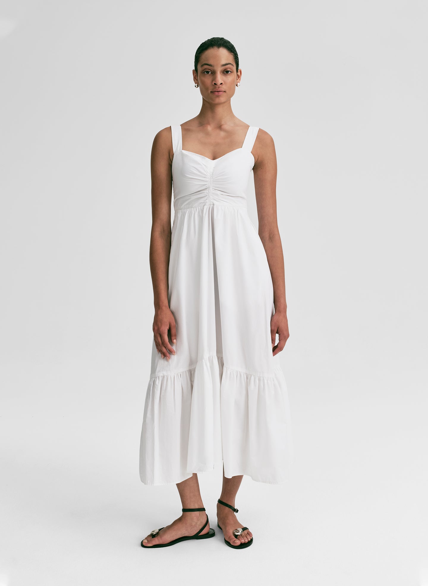 Woman wearing a white midi dress against a plain background