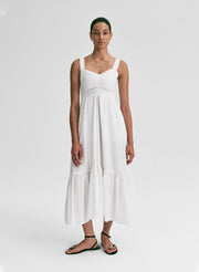 Woman wearing a white midi dress against a plain background