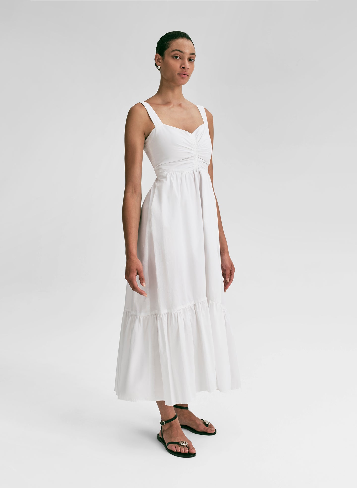 Woman wearing a white midi dress against a plain background