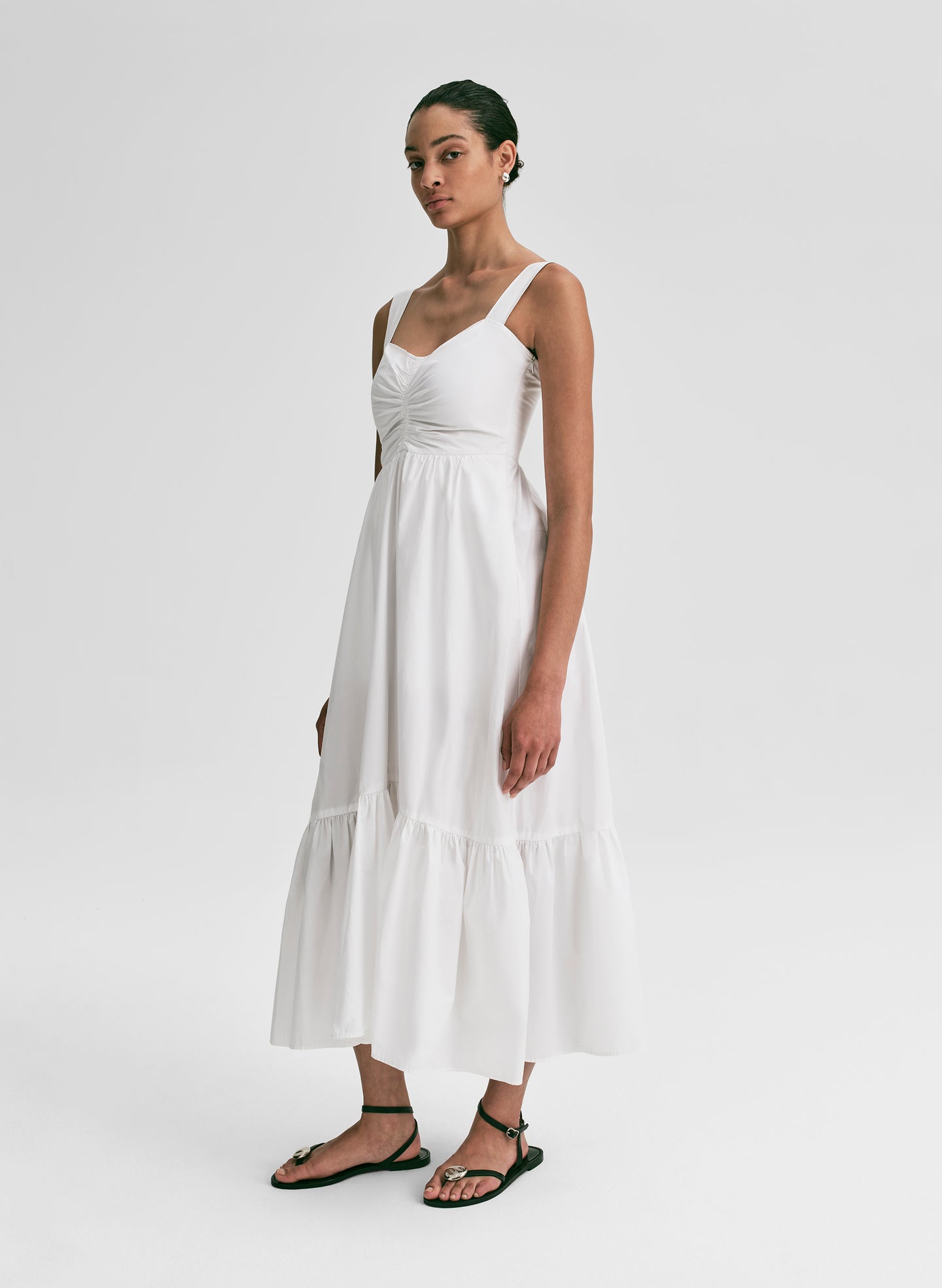 Woman wearing a white midi dress against a plain background