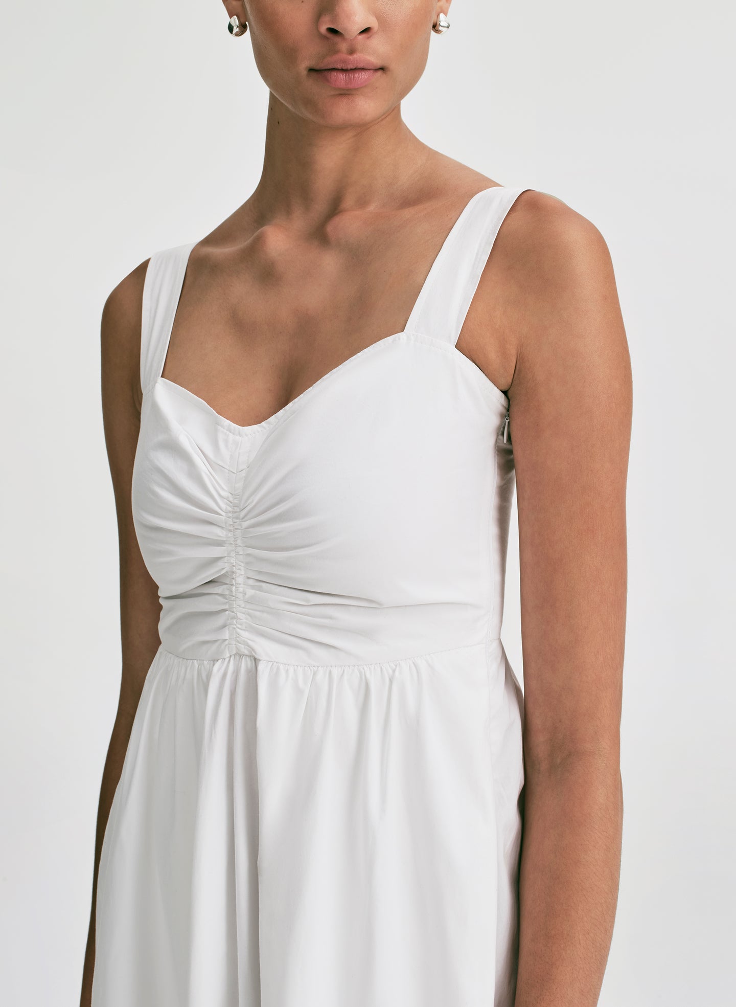Woman wearing a white midi dress against a plain background