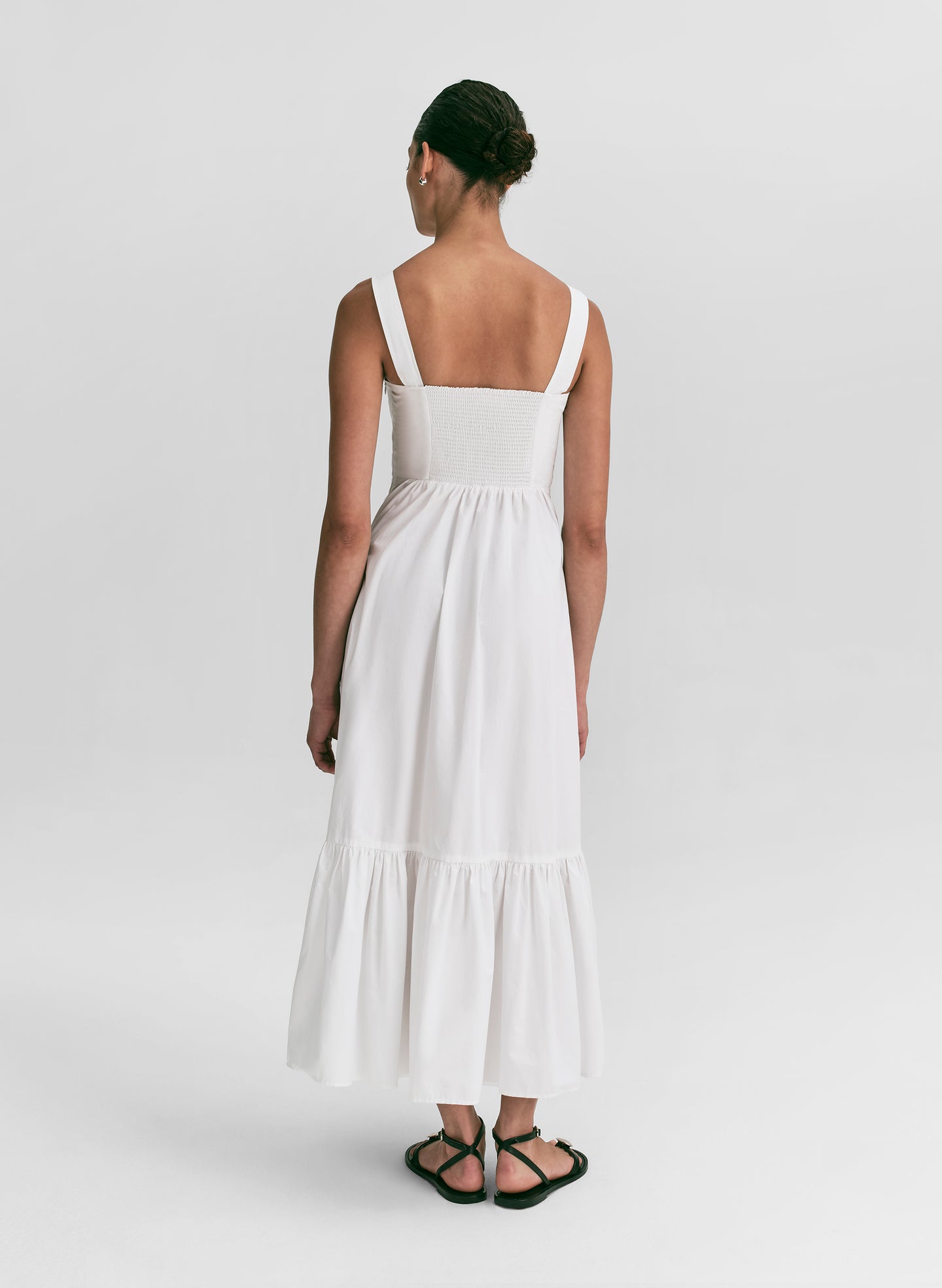 Woman wearing a white midi dress against a plain background