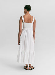 Woman wearing a white midi dress against a plain background