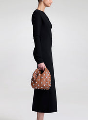 woman wearing black dress and carrying brown studded bag