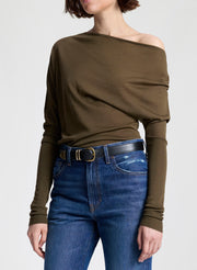 Person wearing an olive green off-shoulder top and blue jeans on a white background