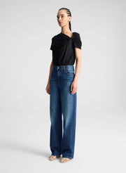 woman wearing black asymmetric draped tee shirt and jeans
