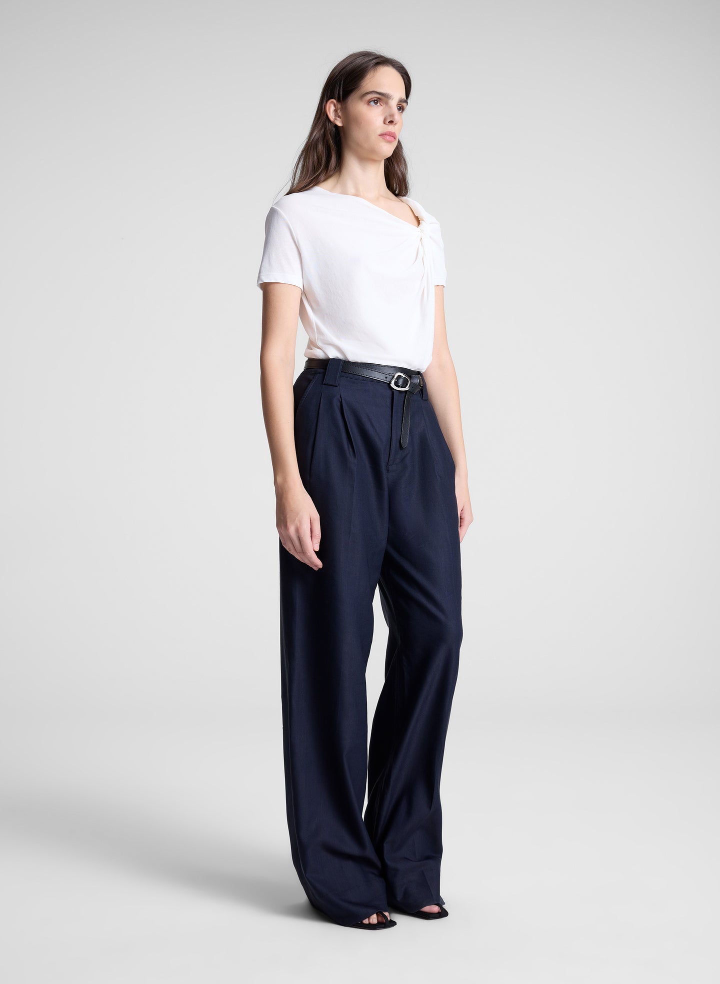woman wearing white asymmetric draped tee and navy blue pants