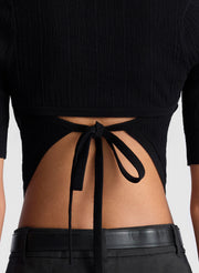 woman wearing black open back fine gauge voile knit top and black linen pants