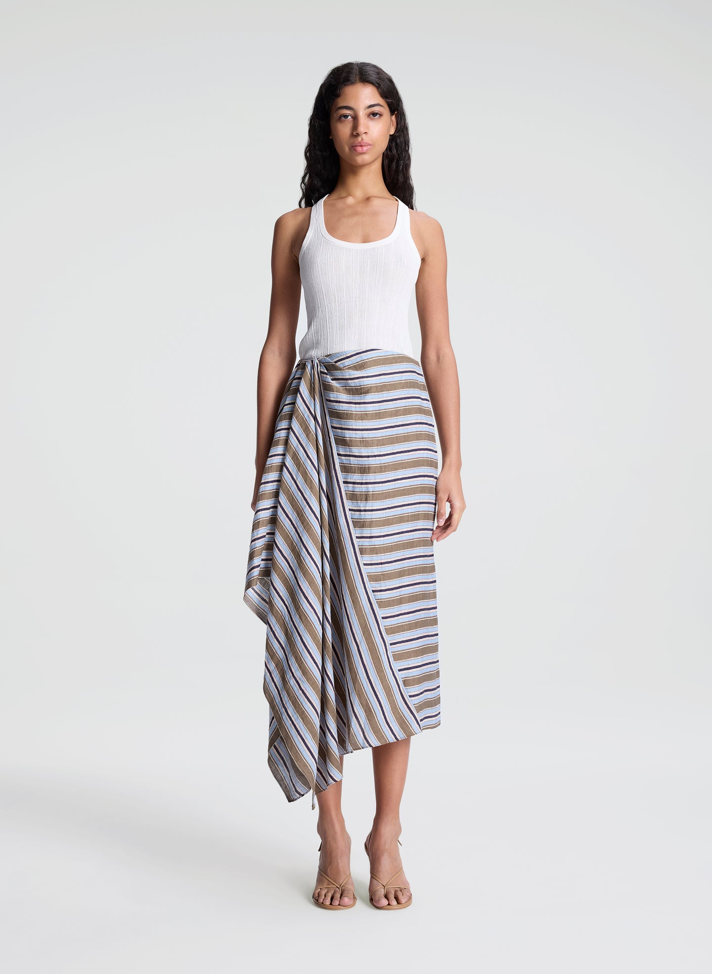 woman wearing white fine gauge tank top and striped midi skirt