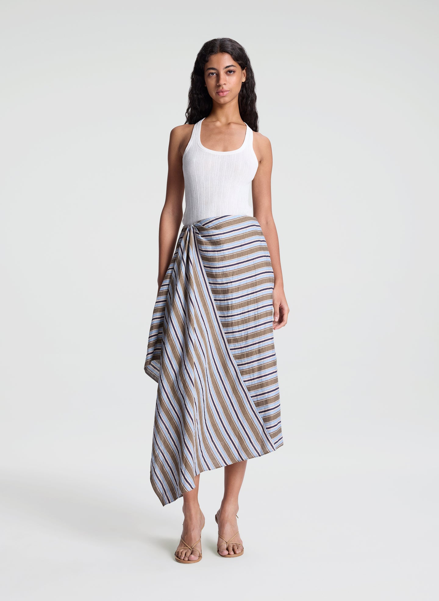 woman wearing white fine gauge tank top and striped midi skirt