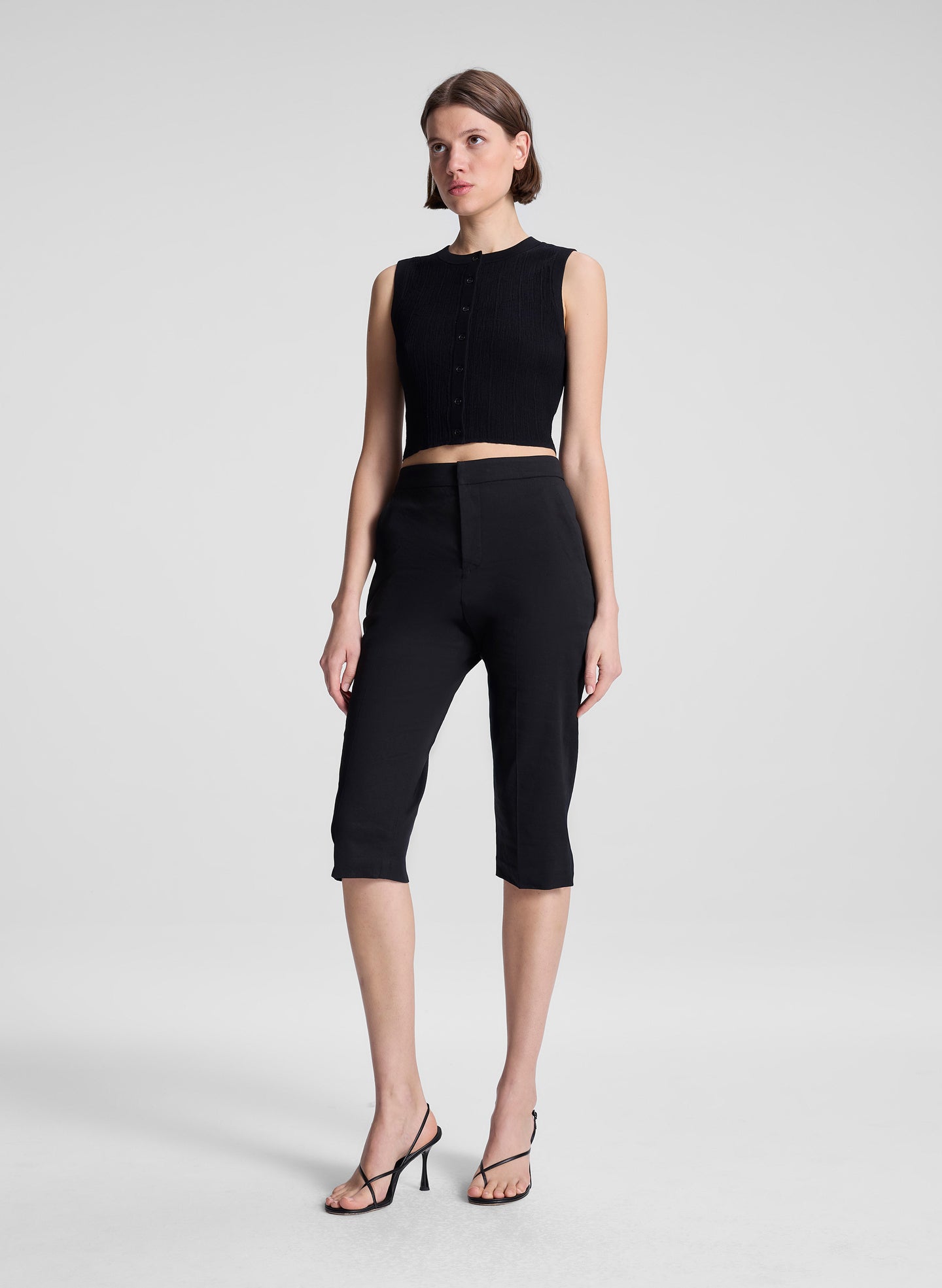 woman wearing black cropped sleeveless fine gauge voile knit top and black capri pants
