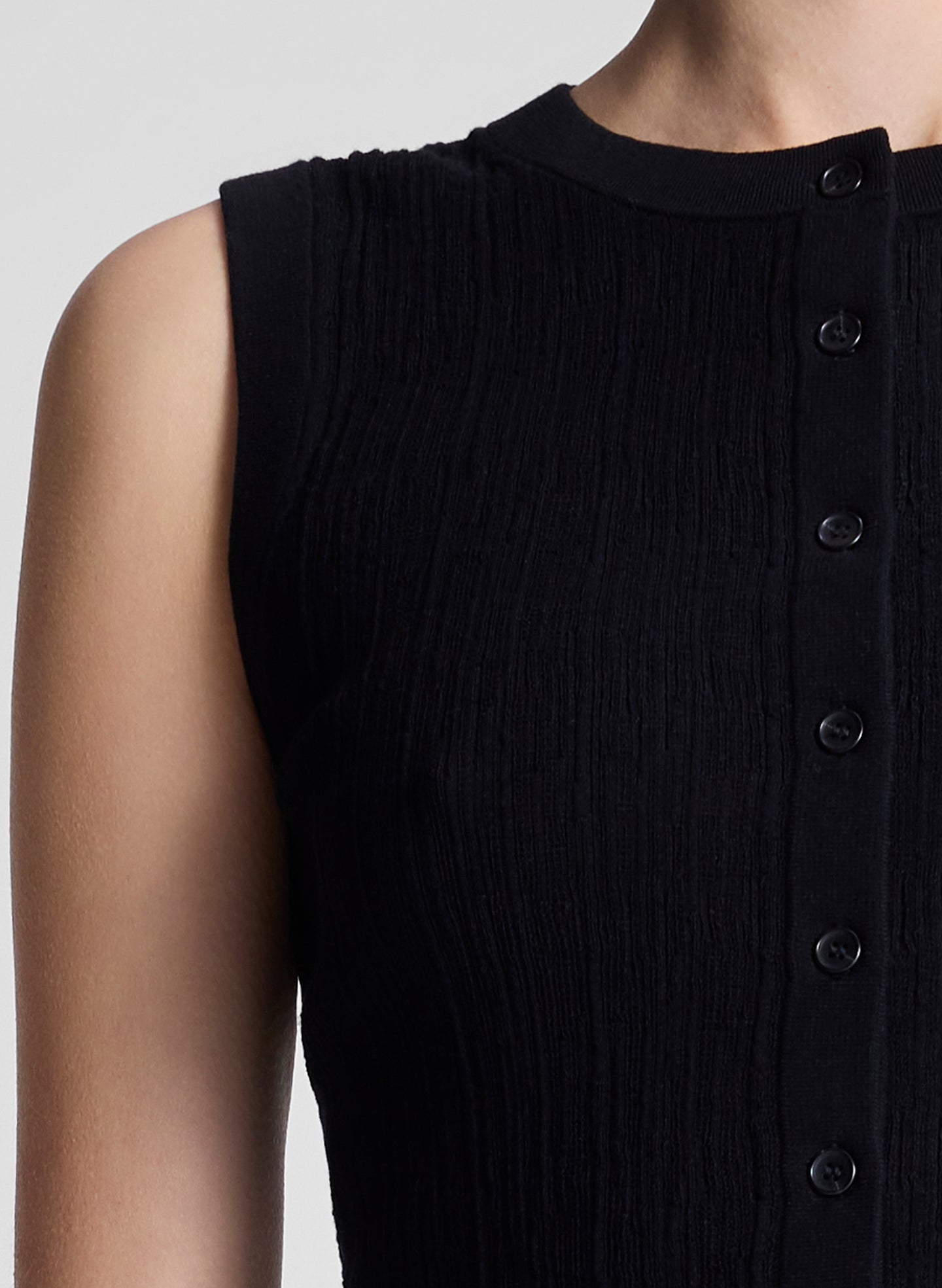 woman wearing black cropped sleeveless fine gauge voile knit top and black capri pants