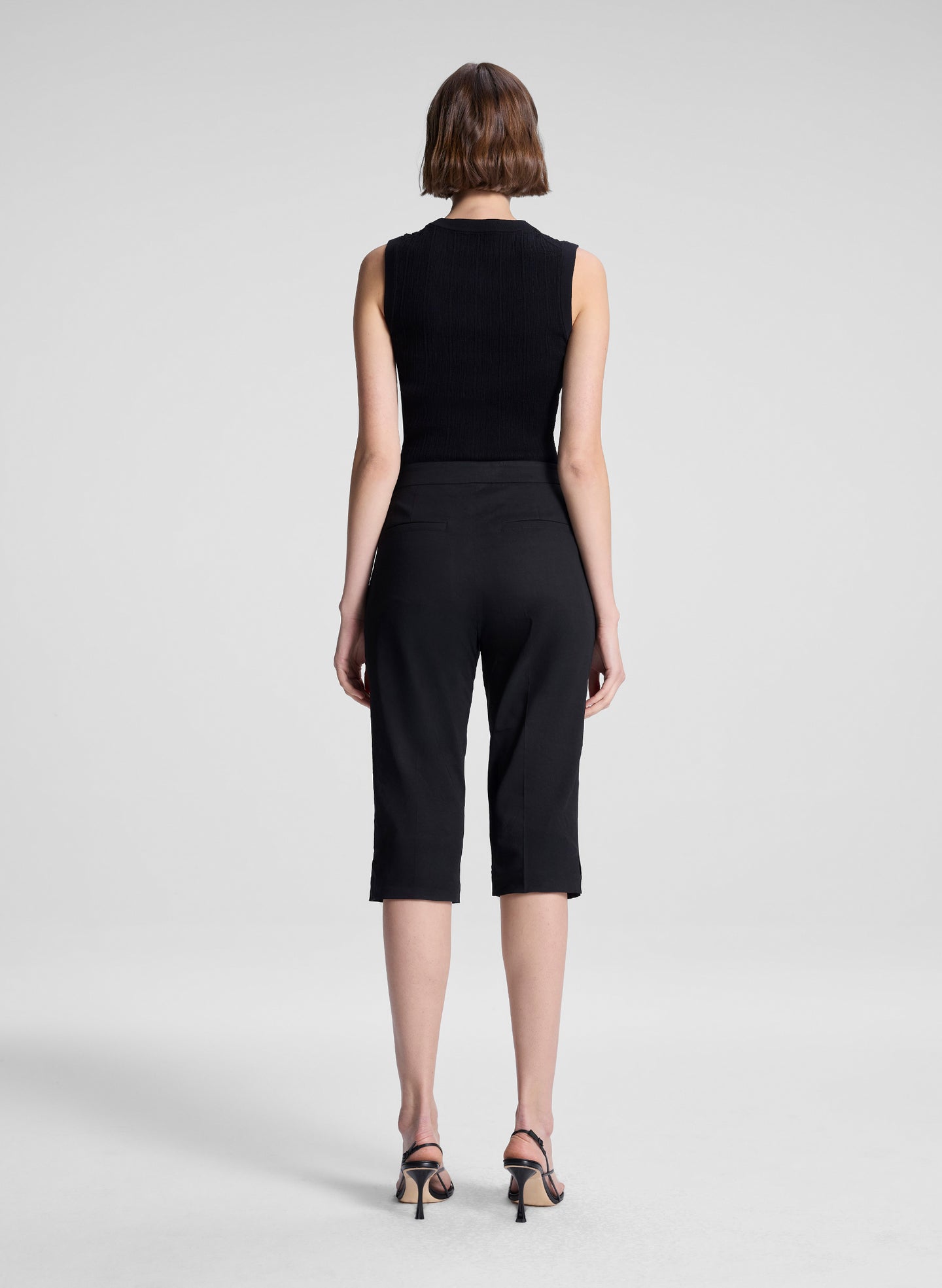 woman wearing black cropped sleeveless fine gauge voile knit top and black capri pants