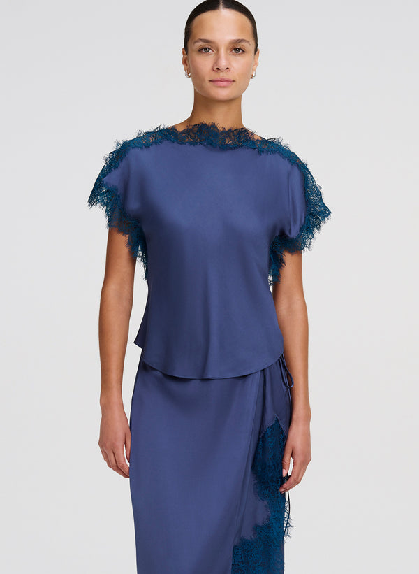 Woman wearing a blue top and skirt with lace details on a white background