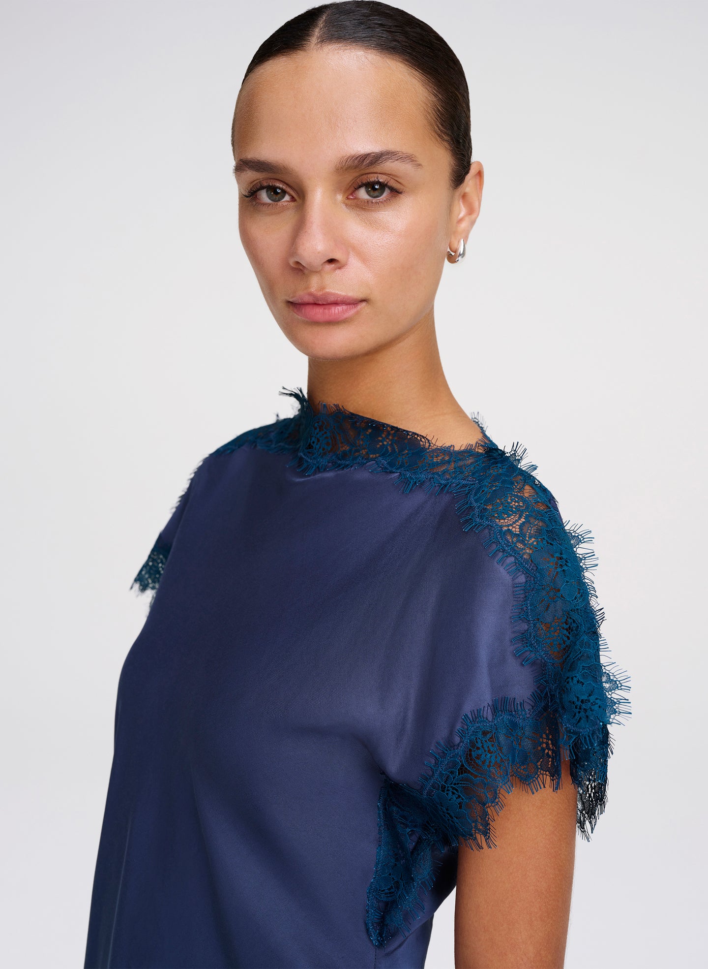 Woman wearing a blue blouse with lace details on a white background