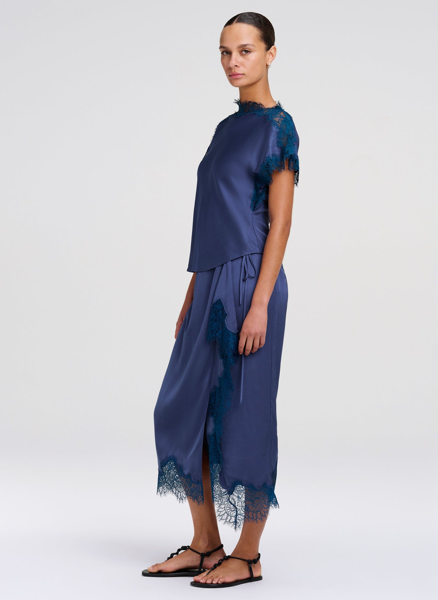 Woman wearing a navy blue outfit with lace details on a white background