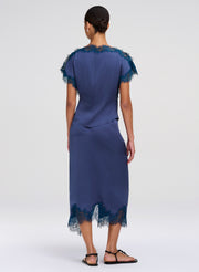 Woman wearing a blue top and skirt with lace details on a white background