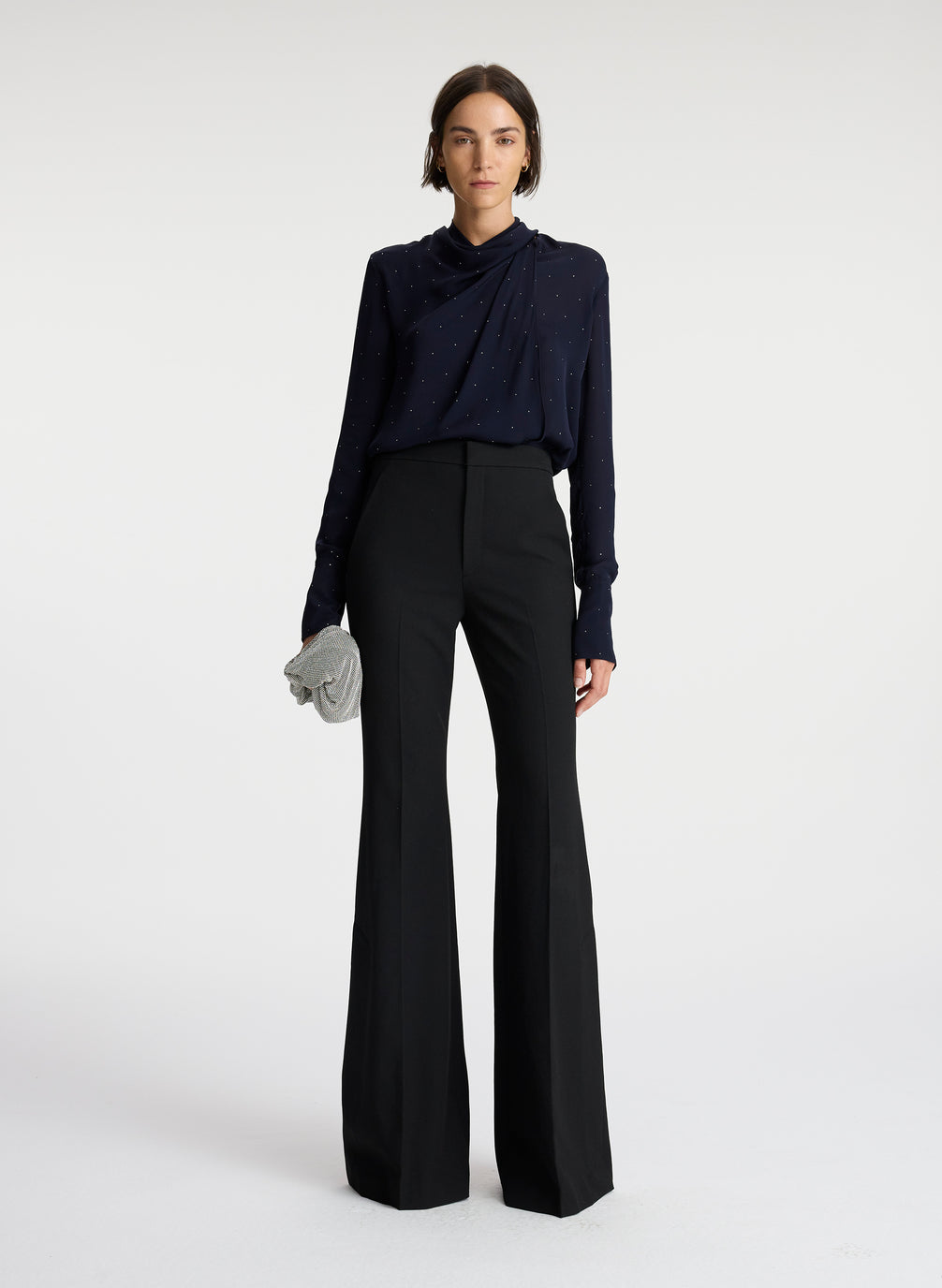 front view of woman wearing navy blue silk long sleeve top with crystal embellishments and black pants