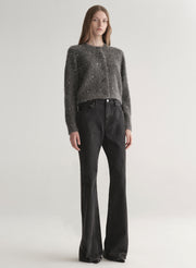 Person wearing a dark gray knit cardigan with embellishments on a plain background