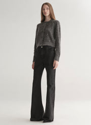 Person wearing a dark gray knit cardigan with embellishments on a plain background