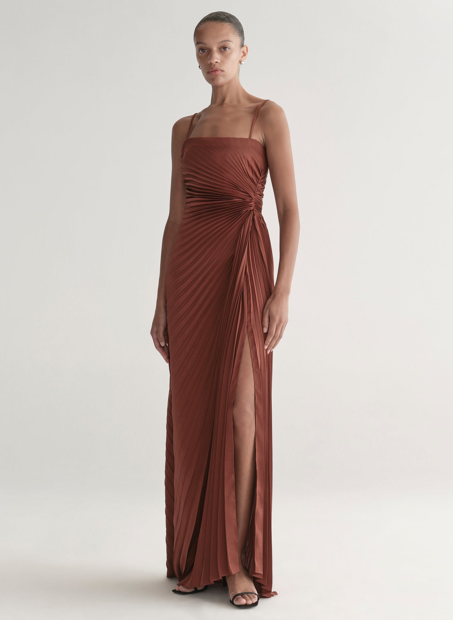 woman wearing strapless pleated gown in a rust hue