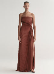 woman wearing strapless pleated gown in a rust hue
