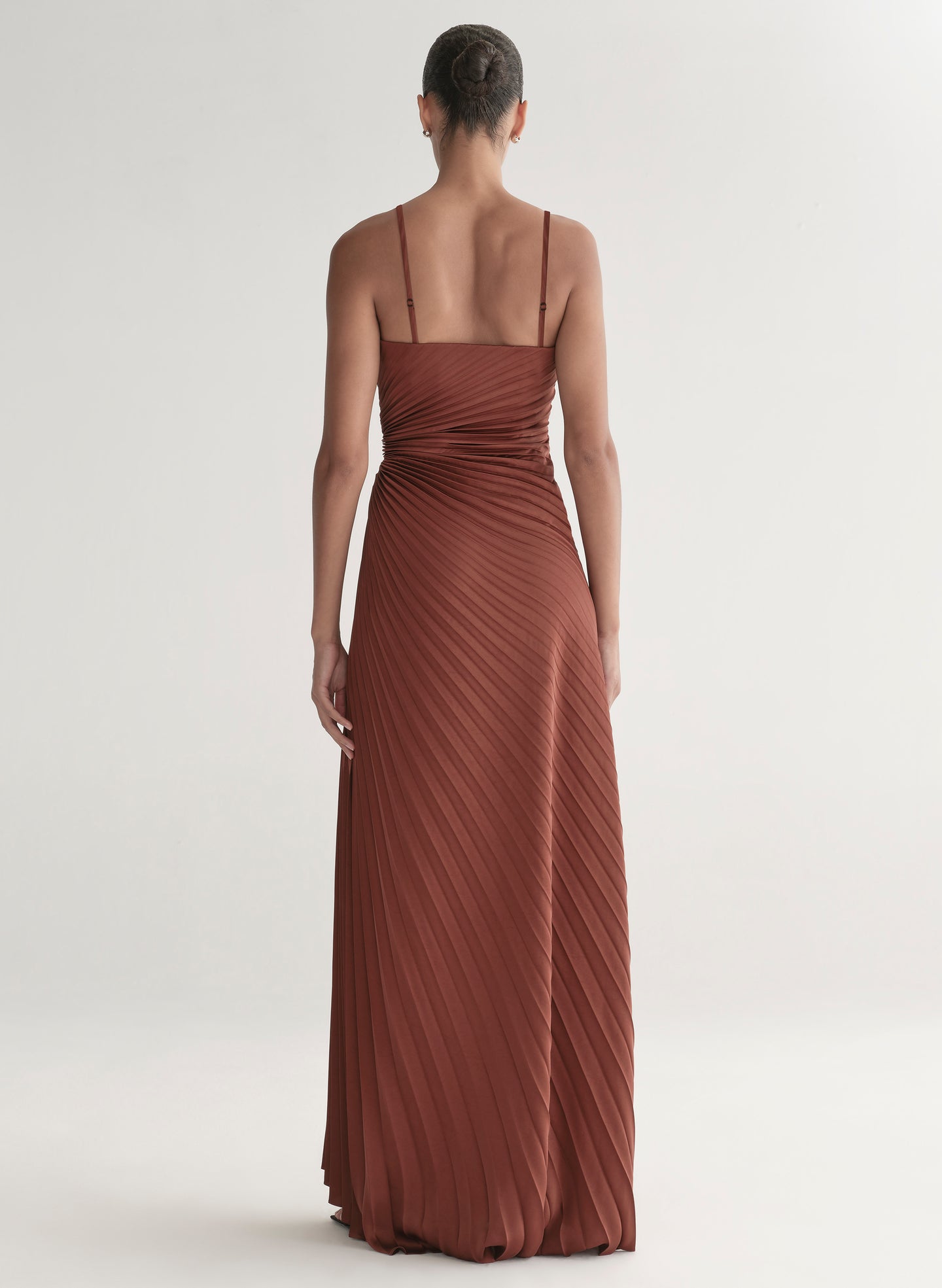woman wearing strapless pleated gown in a rust hue