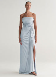 Woman wearing a strapless, light blue gown with a slit on a white background