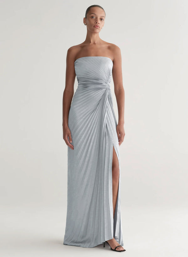Woman wearing a strapless, floor-length gray dress with a slit on a white background