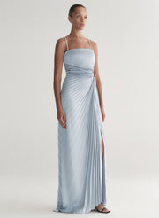 Woman wearing a light blue strapless gown with a slit on a plain background