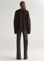 woman wearing brown embellished sweater with black denim jeans