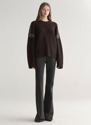 woman wearing brown embellished sweater with black denim jeans