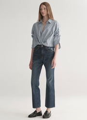 Woman wearing a striped shirt and jeans on a plain background